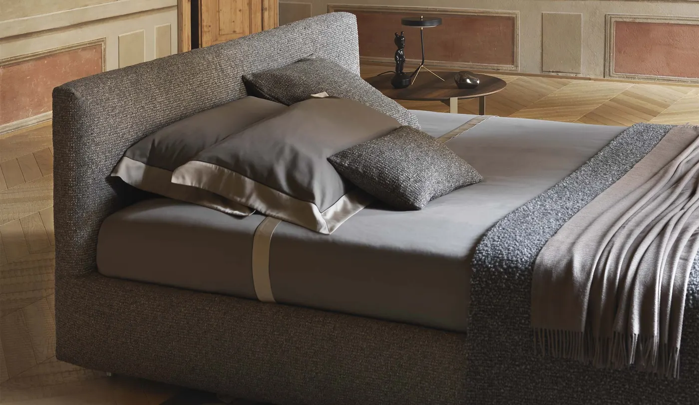 Dettaglio di letto imbottito in tessuto grigio